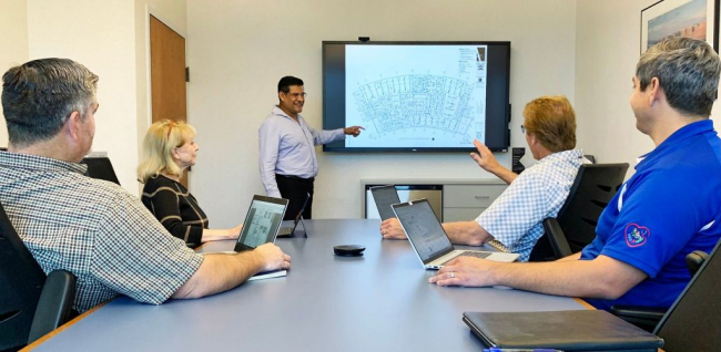 Group of electricians looking at building plans in an office setting
