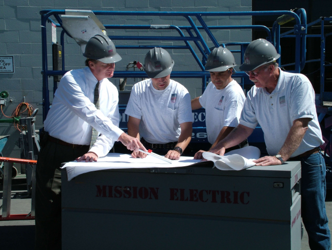 Group of electricians at a work site looking at the electrical plans